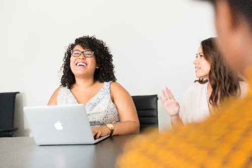 Vrouwen praten met elkaar, vrouw achter laptop lacht