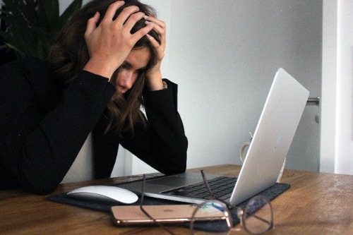 Vrouw met handen in het haar achter laptop